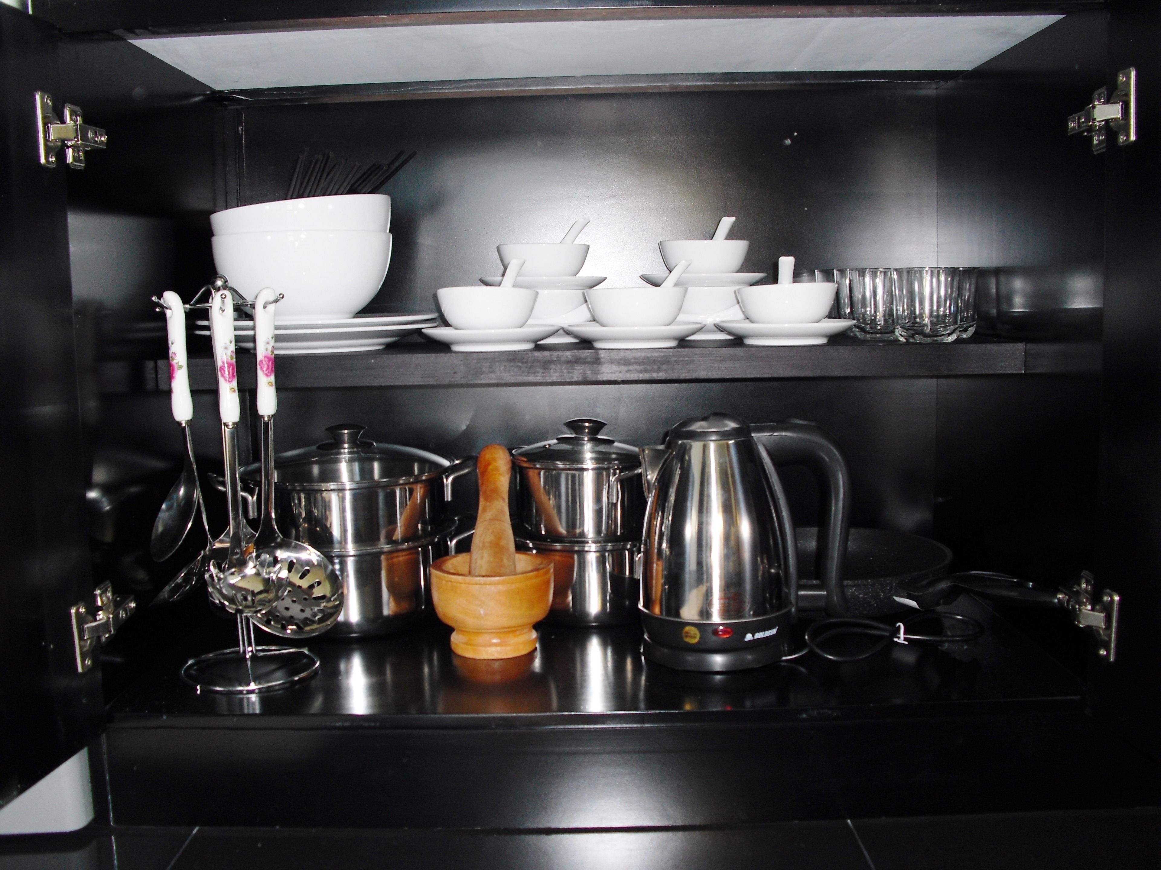 Een keuken met roestvrijstalen apparatuur en keukengerei, waaronder pannen, een koffiezetapparaat en een rasp.