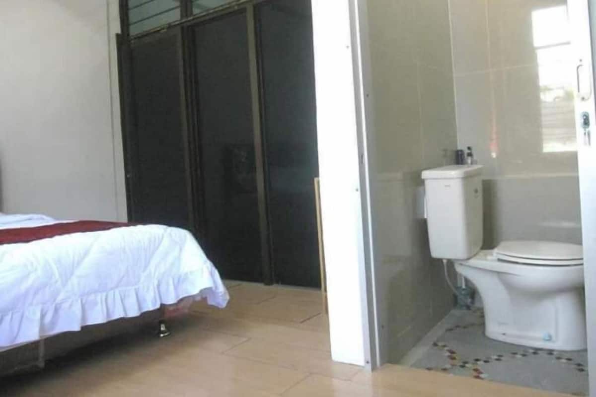A bedroom with a bed, a bathroom with a toilet, and a glass door leading to an outdoor area.