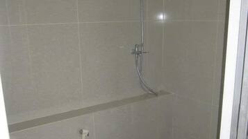 Un baño pequeño con inodoro, ducha y piso de baldosas.