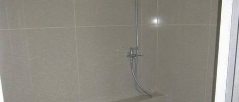 A small bathroom with a toilet, a shower, and a tiled floor.