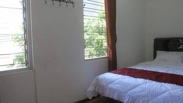 A bedroom with a bed, a window with blinds, and a curtain.