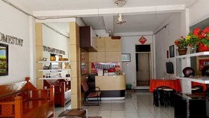 A spacious living area with a reception desk, wooden furniture, and a tiled floor. - Providence Homestay (Surabaya)