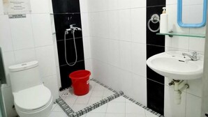 A small bathroom with a toilet, a sink, and a shower area. - Providence Homestay (Surabaya)