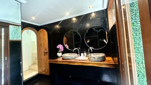 A modern bathroom with a wooden vanity, two round mirrors, and a potted orchid. - The Apartment Umalas (Keroboken Kelod)