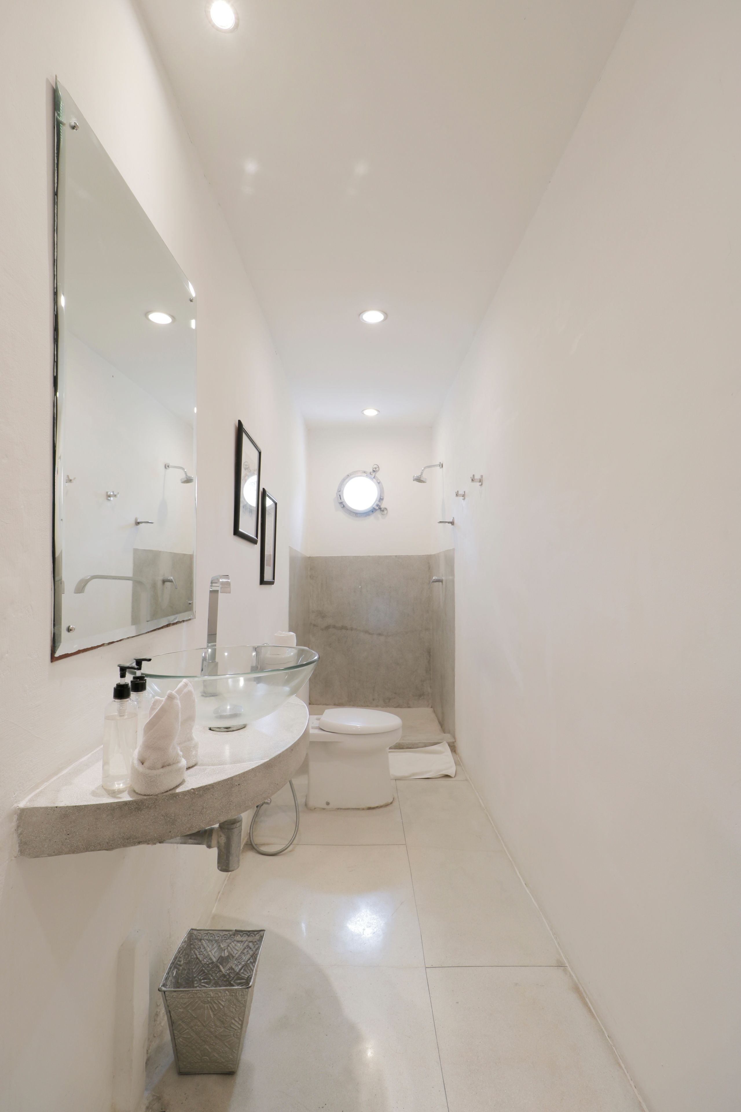 A modern bathroom with a glass sink, a toilet, and a shower area.