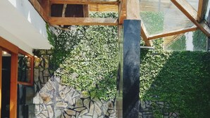 A modern outdoor bathroom with a stone wall, a large white basin, and a glass enclosure. - The Apartment Umalas (Keroboken Kelod)