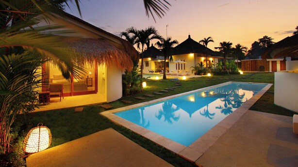 A resort with a swimming pool, thatched-roof structures, and well-lit outdoor areas. - The Apartment Umalas (Keroboken Kelod)
