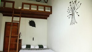 A bedroom with a bunk bed, a ladder, a wall-mounted artwork, and a wooden door. - Sinharaja Forest Edge (Deniyaya)
