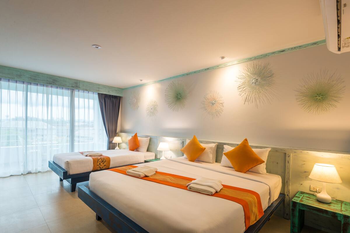 Een hotelkamer met twee bedden, een nachtkastje met een lamp en decoratieve wandlampen.