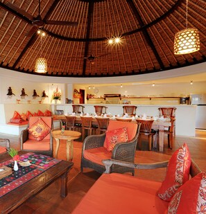 A spacious dining area with wooden furniture and a thatched roof ceiling.