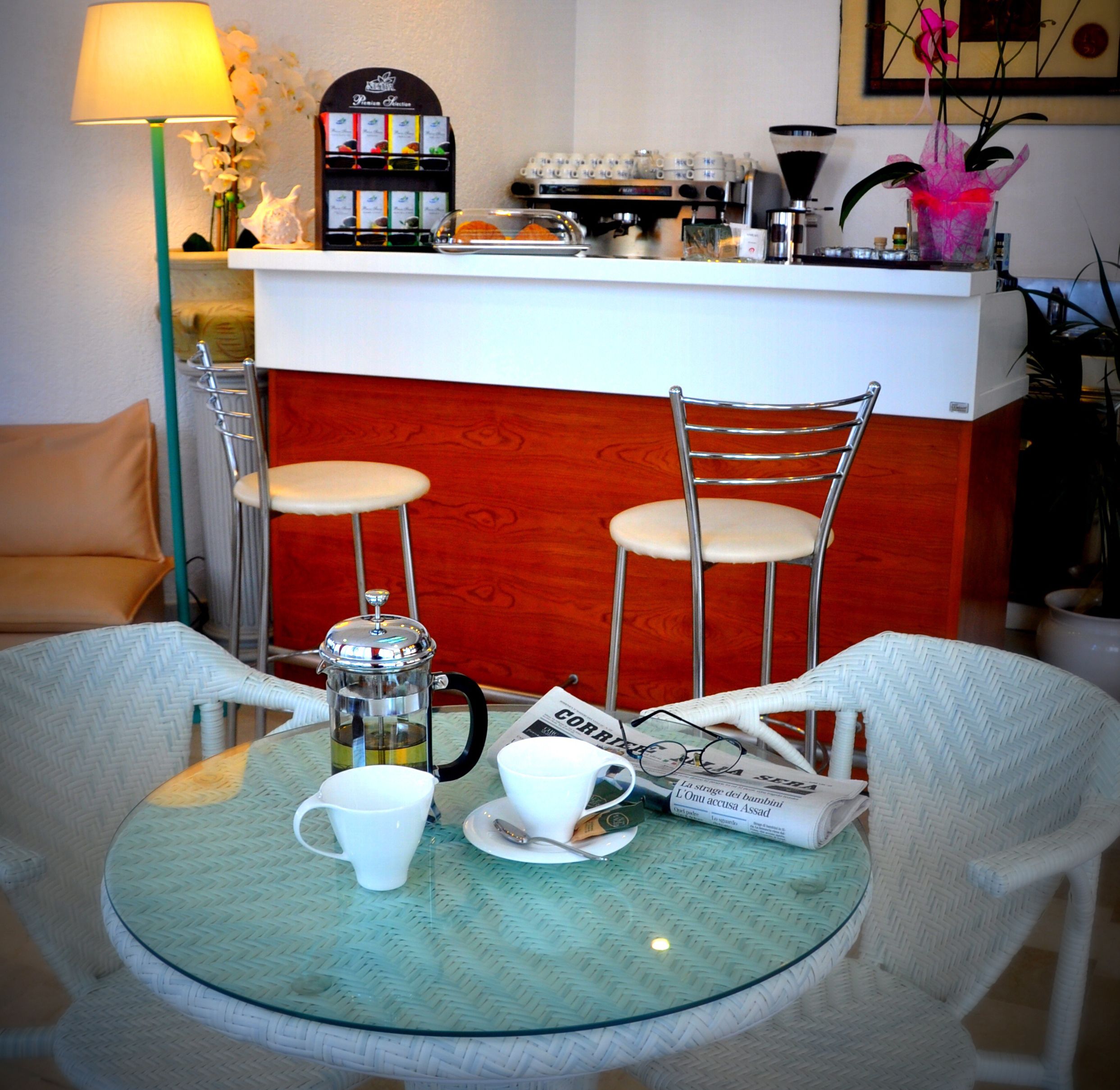 A cozy seating area with a glass table, two chairs, a coffee maker, and a menu stand.
