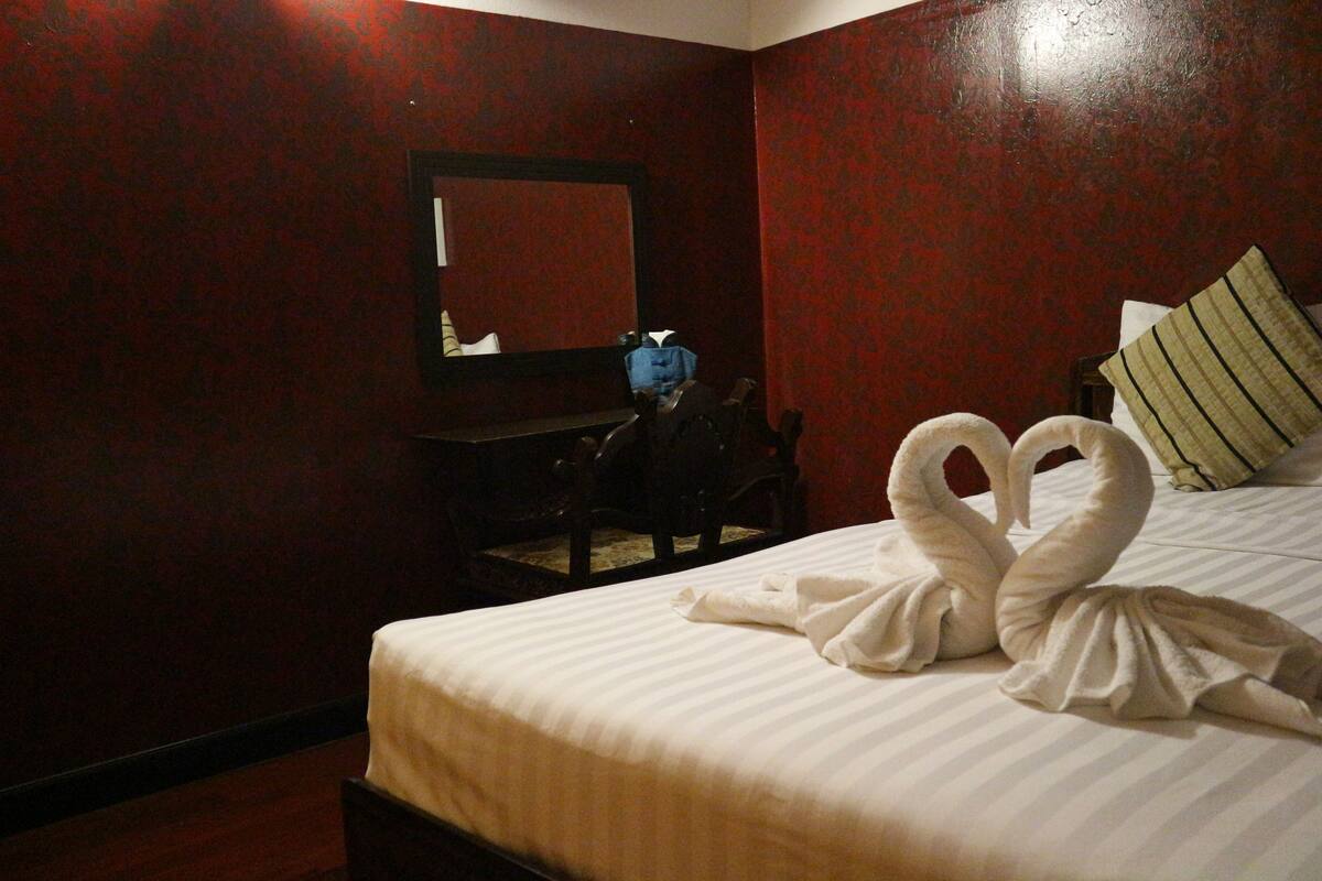 A hotel room with a bed, a desk, and a mirror.