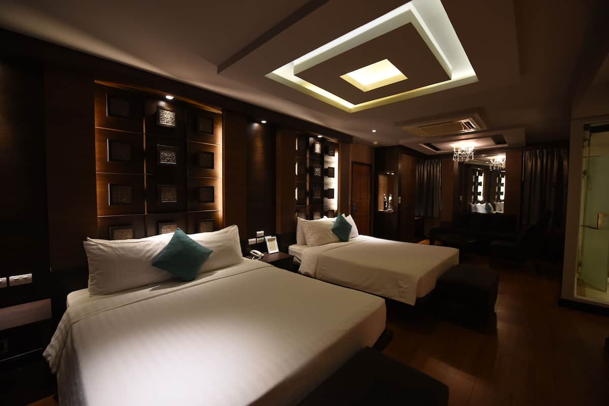 A hotel room with two beds, a skylight, a chandelier, and a wooden panel wall.