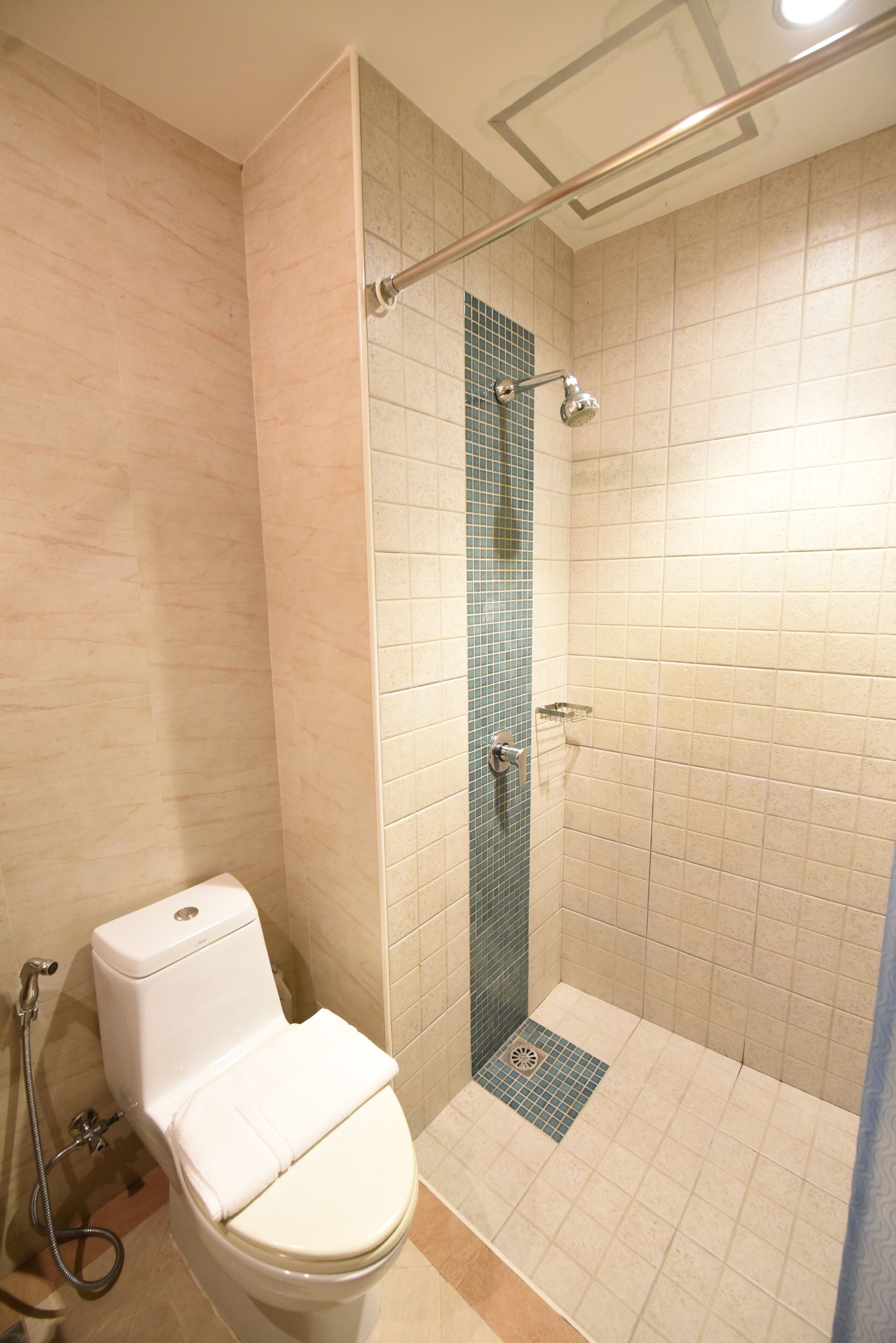 A bathroom with a toilet, a shower with a glass door, and a tiled floor.