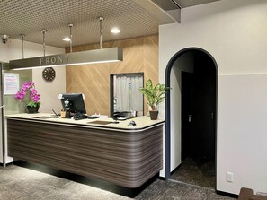 A reception desk with a clock, a computer, and a plant. - HOTEL LiVEMAX BUDGET Mihara Ekimae (Mihara)