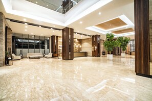 A spacious lobby with a high ceiling, large windows, and a polished marble floor. - Swiss-Belhotel Karawang (Karawang)