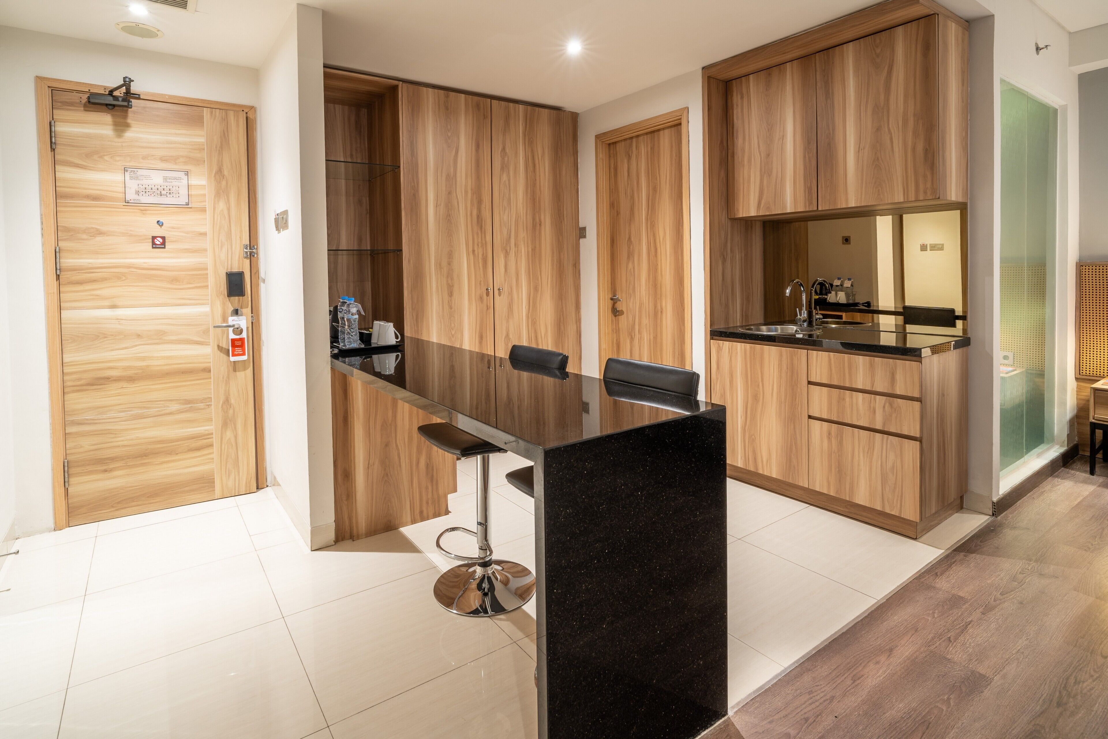 A modern kitchen with wooden cabinets, a black countertop, and a bar stool.