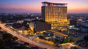 Un hotel moderno con un llamativo letrero de Swiss-Belhotel, rodeado de infraestructura urbana y calles iluminadas.
