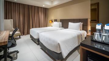 Une chambre d’hôtel avec deux lits, un bureau, une chaise, un coin café et une grande fenêtre avec des rideaux.