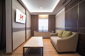 Une chambre d’hôtel moderne avec une grande fenêtre, un canapé, une table basse et un panneau sur le mur.
