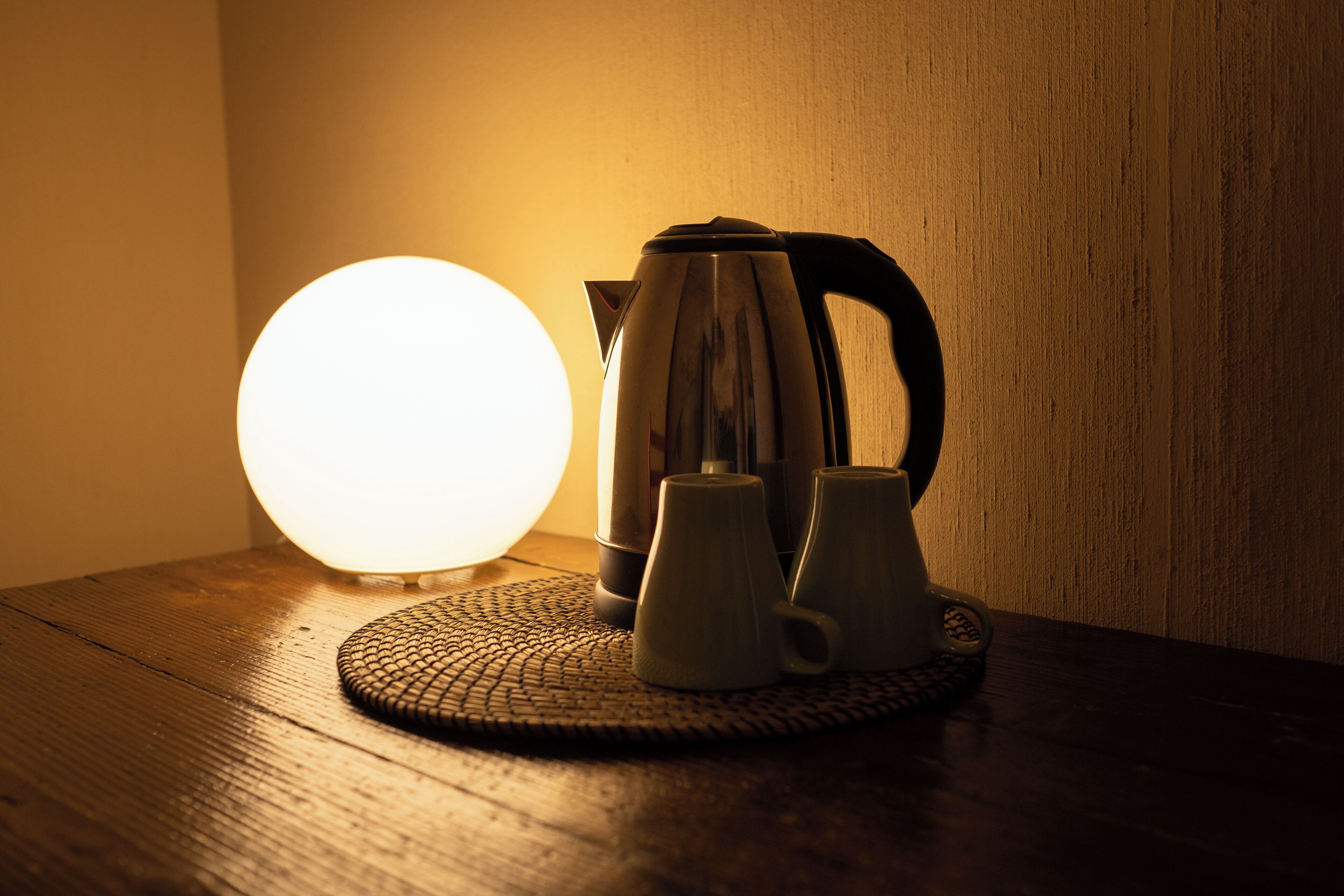 A table with a kettle, two mugs, and a glowing lamp.