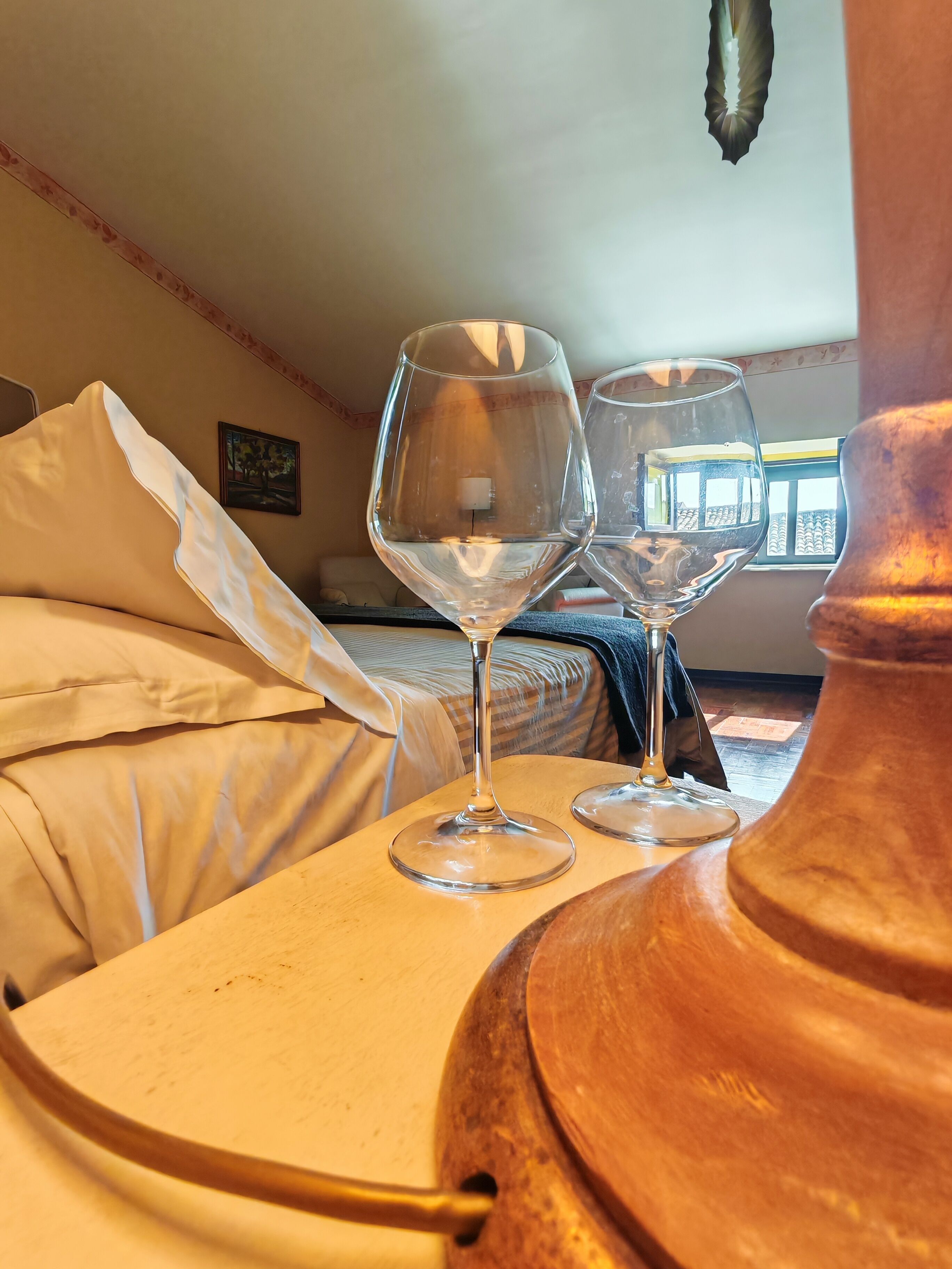 Une chambre avec un lit, deux verres à vin posés sur un plateau et un grand pot en cuivre.