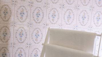 Un baño con un perchero blanco frente a una pared con un diseño de azulejos florales.