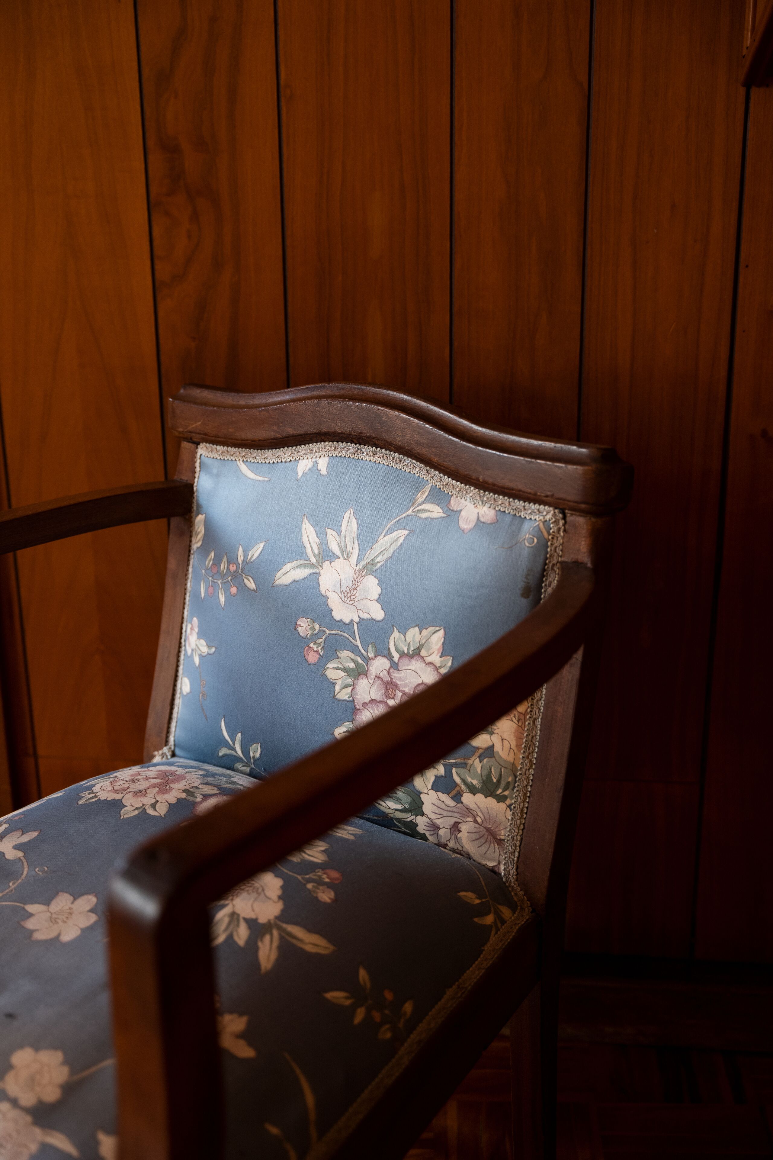 Une chaise en bois avec un coussin à motifs floraux, adossée à un mur en bois.