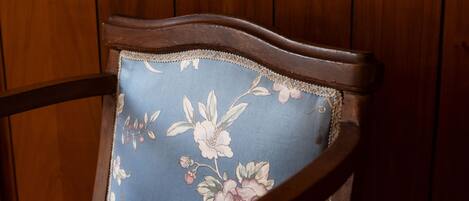 A wooden chair with a floral cushion against a wooden wall.