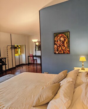 A bedroom with a large bed, a painting on the wall, and a desk with a chair. - Liodoro Bed and Breakfast (Catania)