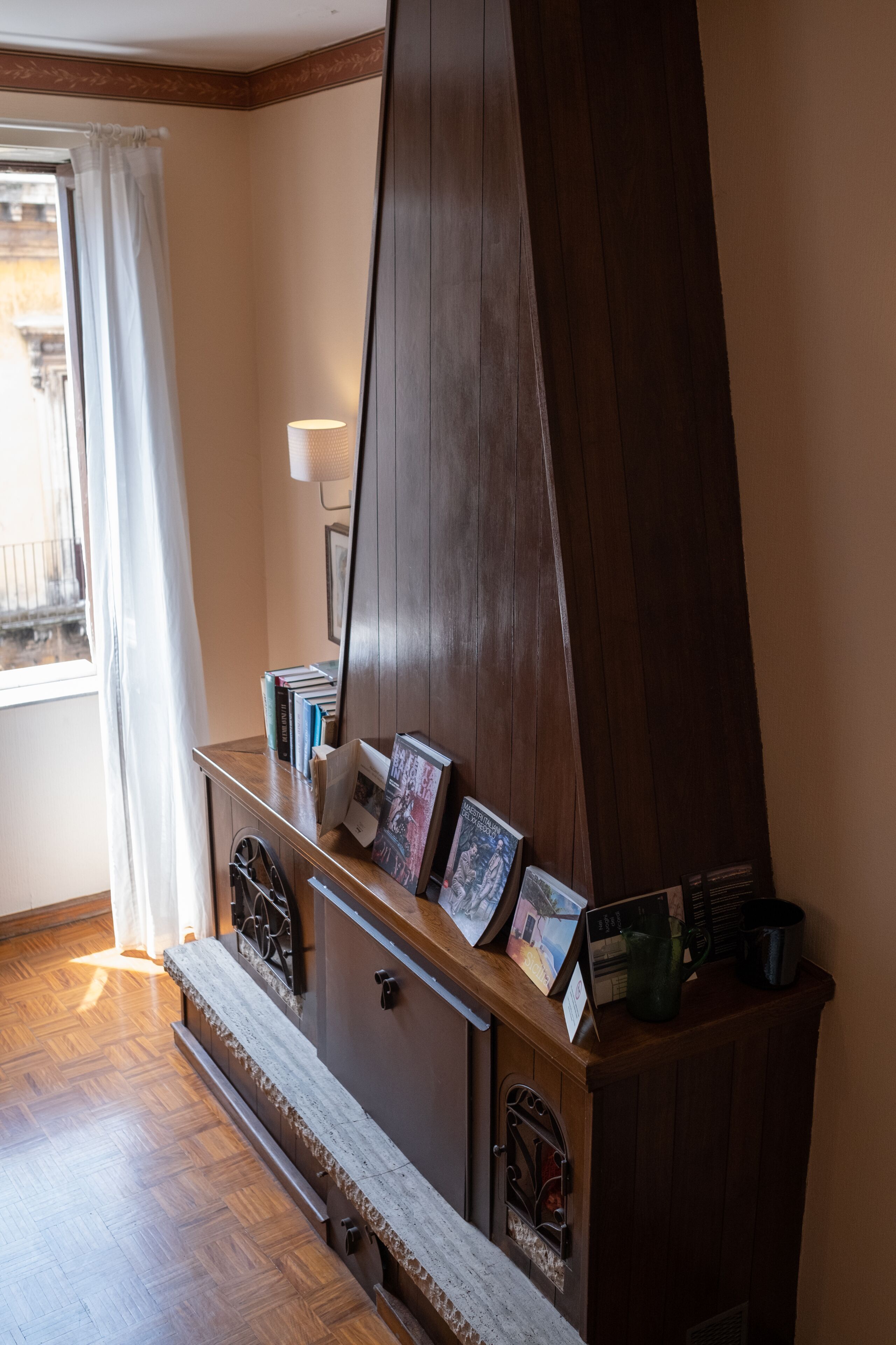 Un meuble en bois avec un miroir, des livres et des objets décoratifs.
