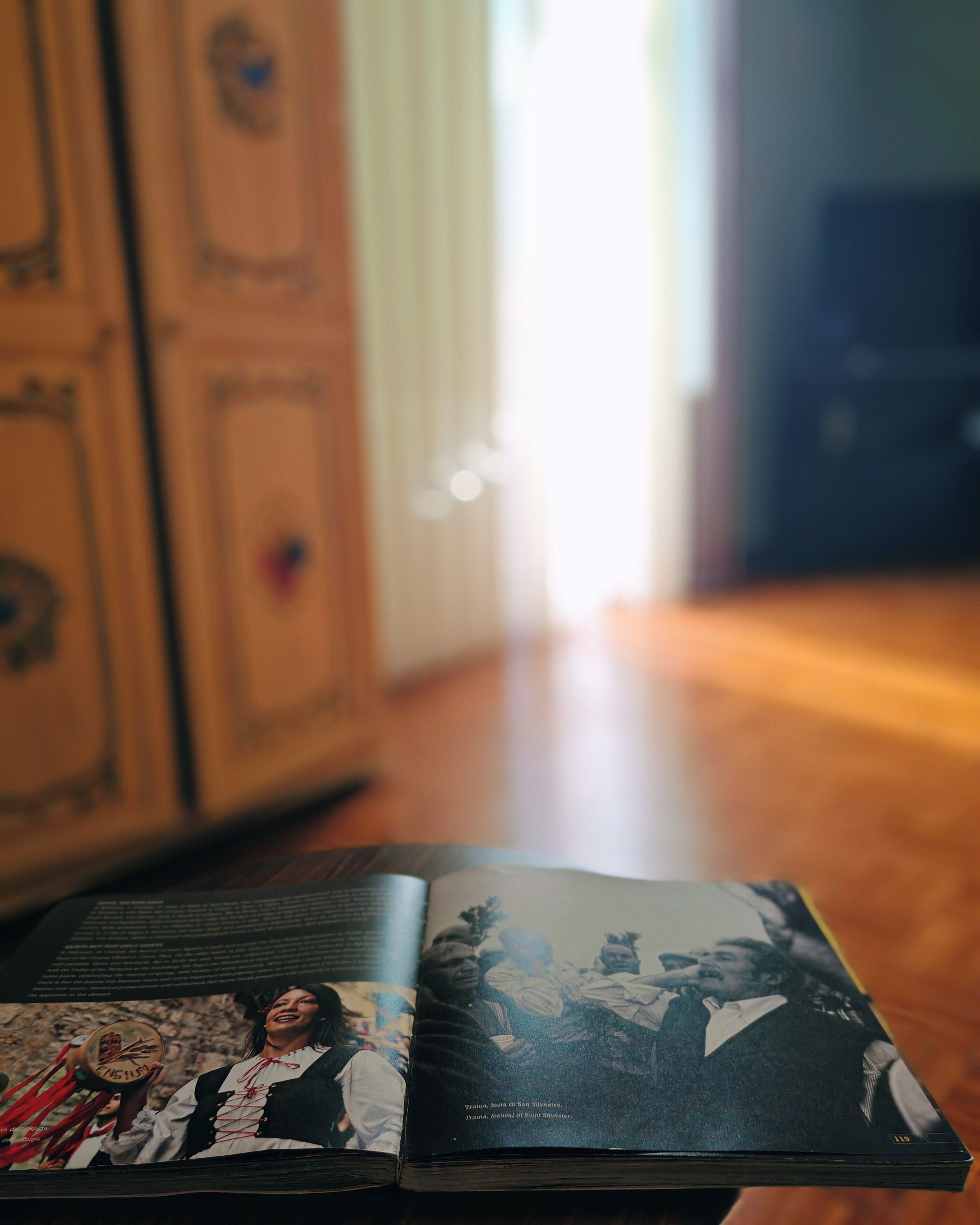 An open book on a wooden table with a photograph on the left page and text on the right page.