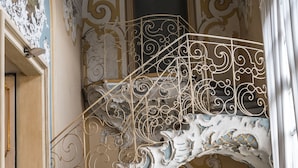 Una escalera ornamentada con barandillas de metal intrincadas y un piso de mármol.
