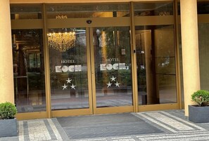 A hotel entrance with glass doors, a chandelier, and a star logo. - Hotel Koch (Ketrzyn)