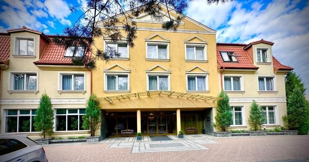 Ein mehrstöckiges Hotel mit symmetrischer Fassade, großen Fenstern und einem zentralen Eingang mit Vordach.