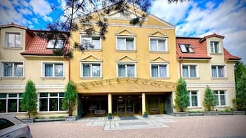 Ein mehrstöckiges Hotel mit symmetrischer Fassade, großen Fenstern und einem zentralen Eingang mit Vordach.