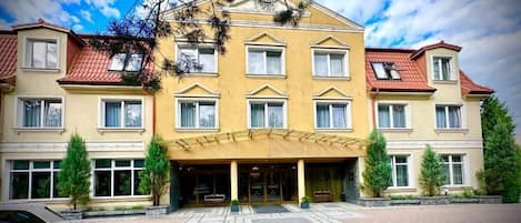Un hotel de varios pisos con fachada simétrica, ventanas amplias y una entrada central con dosel.