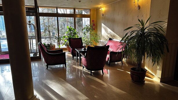 Un vestíbulo amplio con techo alto, ventanas grandes y una variedad de opciones de asientos, incluyendo sillones y una mesa.