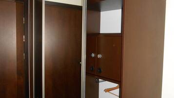 A walk-in closet with a mirrored closet door, a wooden wardrobe, and a green carpet.
