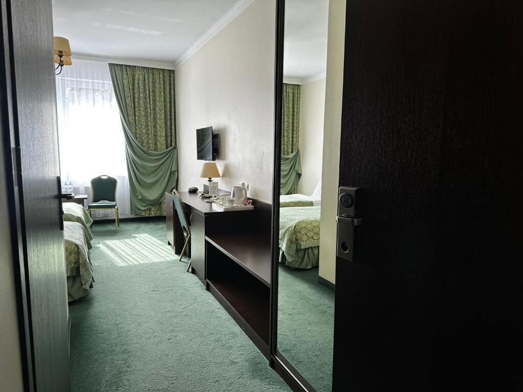 Una habitación de hotel con una cama, un escritorio con lámpara, una silla y un televisor.