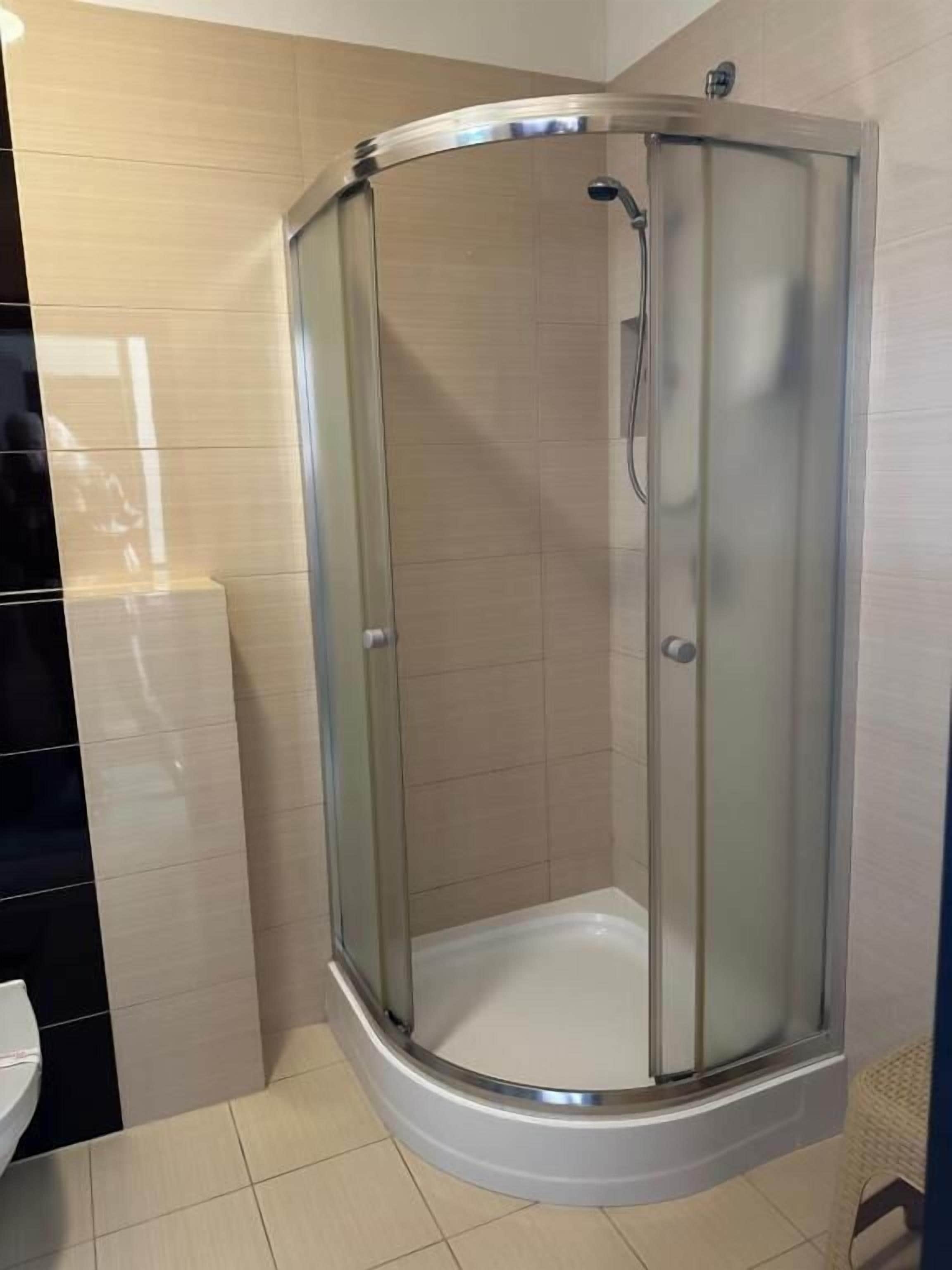 A corner shower with a glass door and a white base.