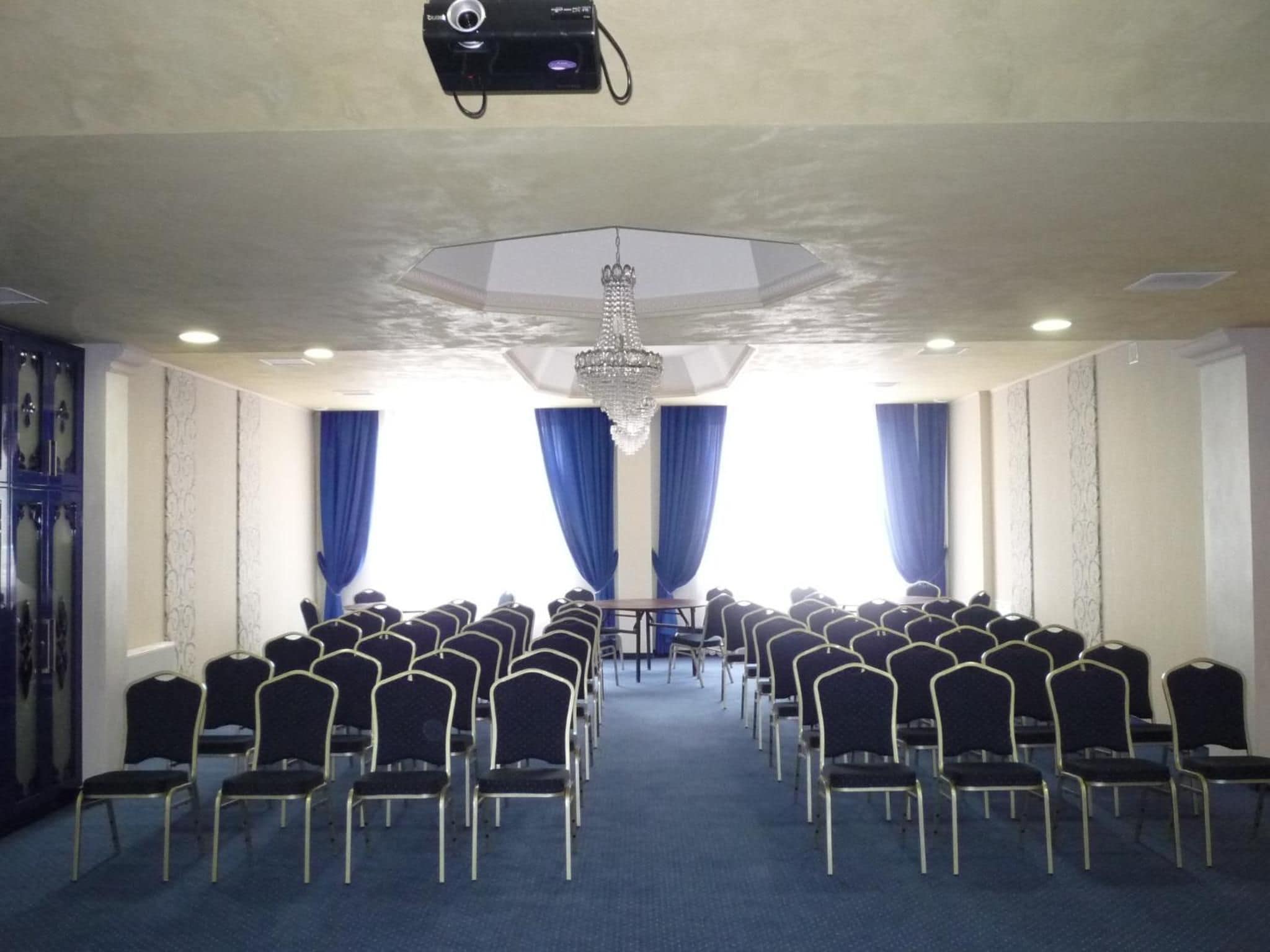 A conference room with rows of chairs, a projector, and a chandelier.