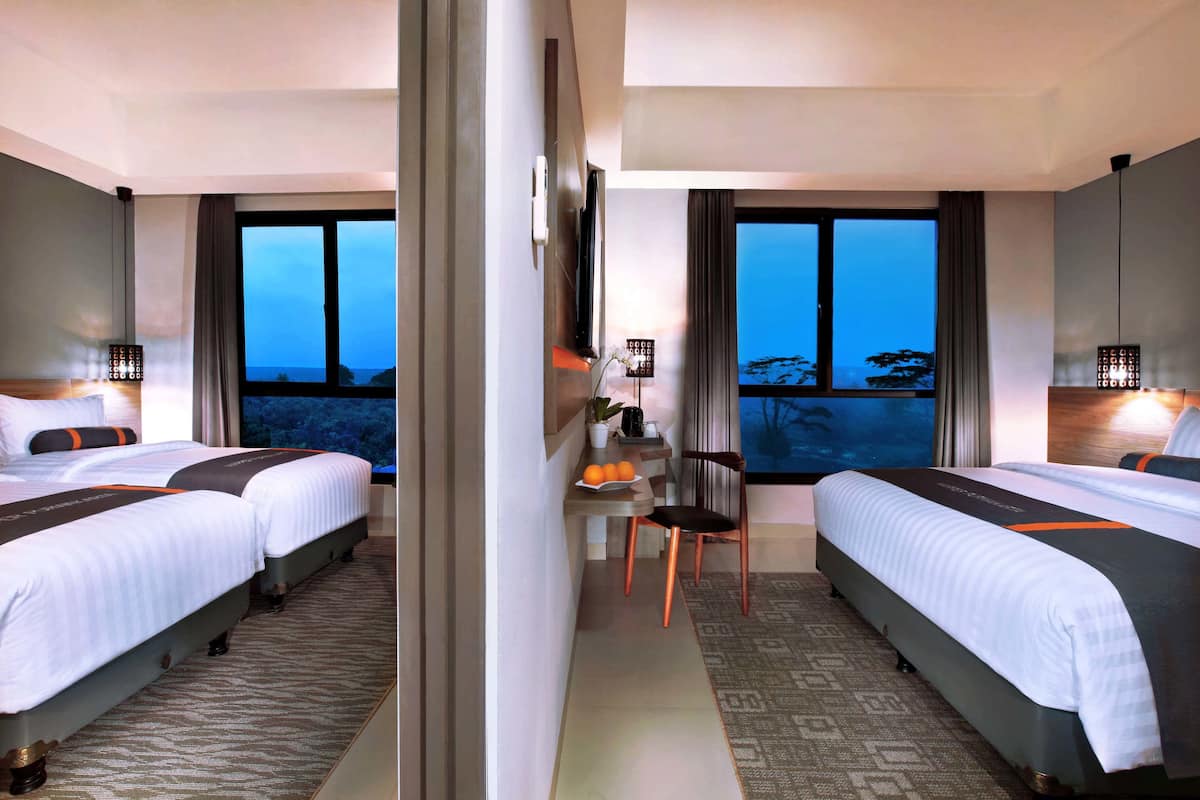 Een hotelkamer met twee bedden, een bureau en uitzicht op de skyline.