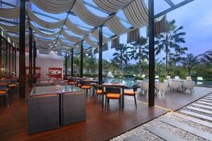 A spacious outdoor lounge area with multiple seating arrangements, a pool, and a view of palm trees.