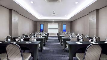 A conference room with tables and chairs, a projector screen, and a presentation screen.