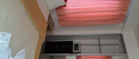 Quarto de hotel com uma cama, um pequeno aquecedor preto e um espelho.