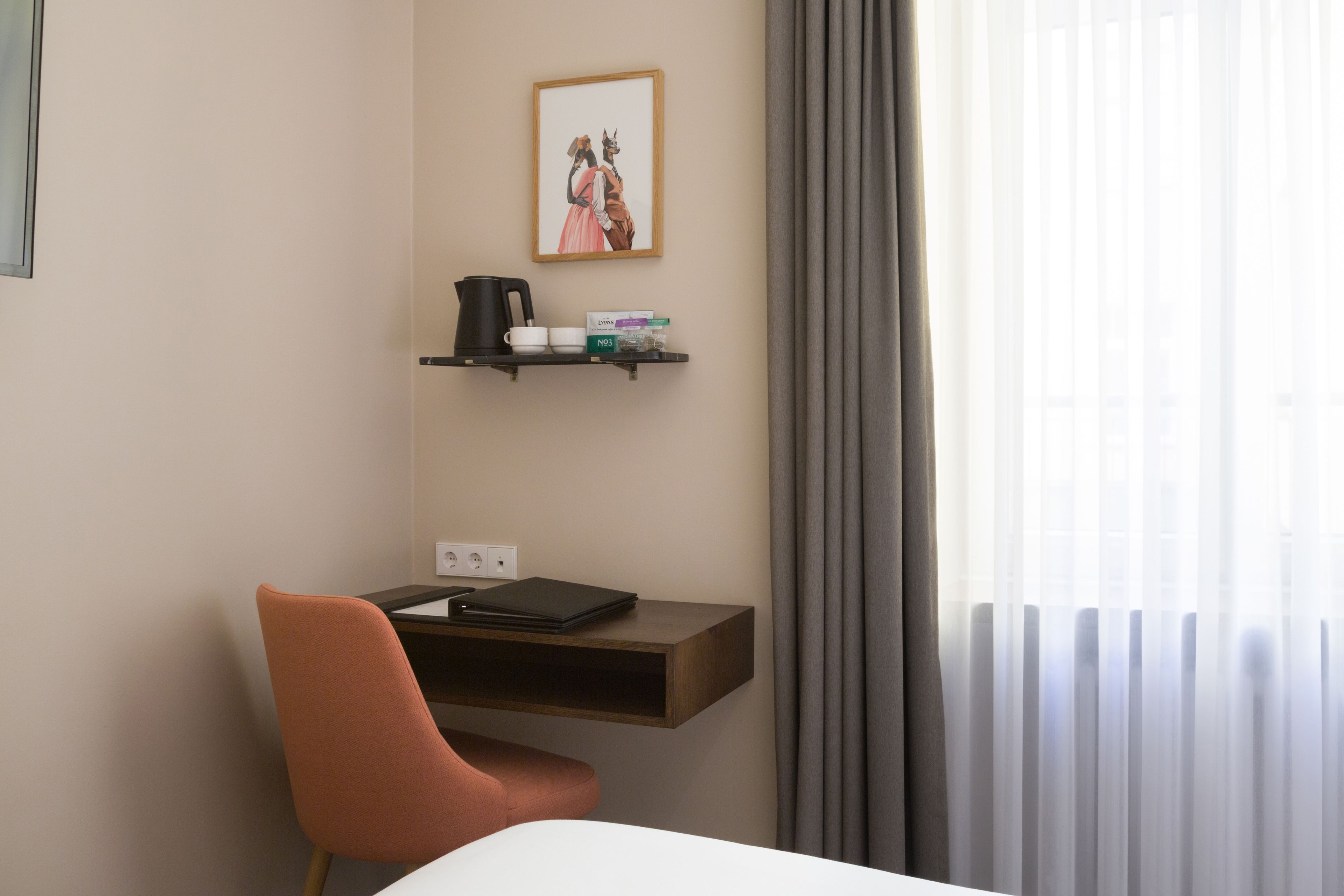 A hotel room with a desk, chair, and a window with curtains.