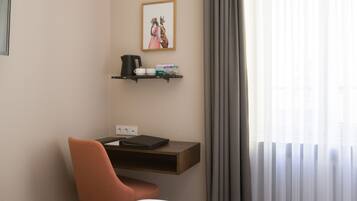 A hotel room with a desk, chair, and a window with curtains.