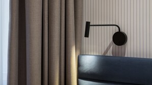 Una habitación moderna con una cama, cortinas y una lámpara fijada a la pared.