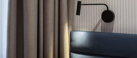 A modern room with a bed, curtains, and a wall-mounted light fixture.